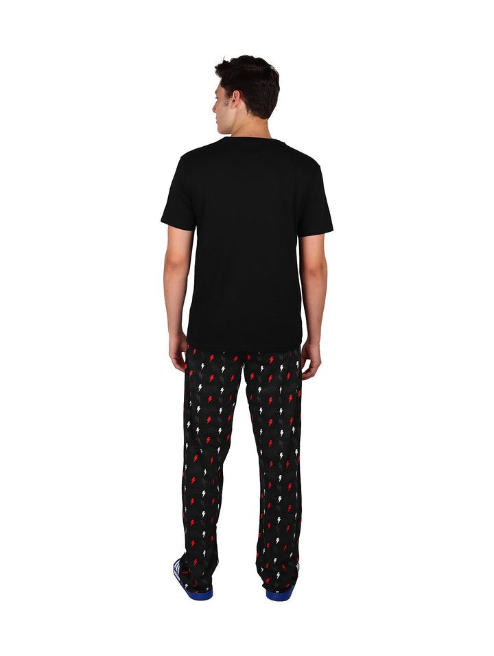 Hombre vistiendo pijama de pantalón largo negro con estampado de rayos rojos y camiseta negra.