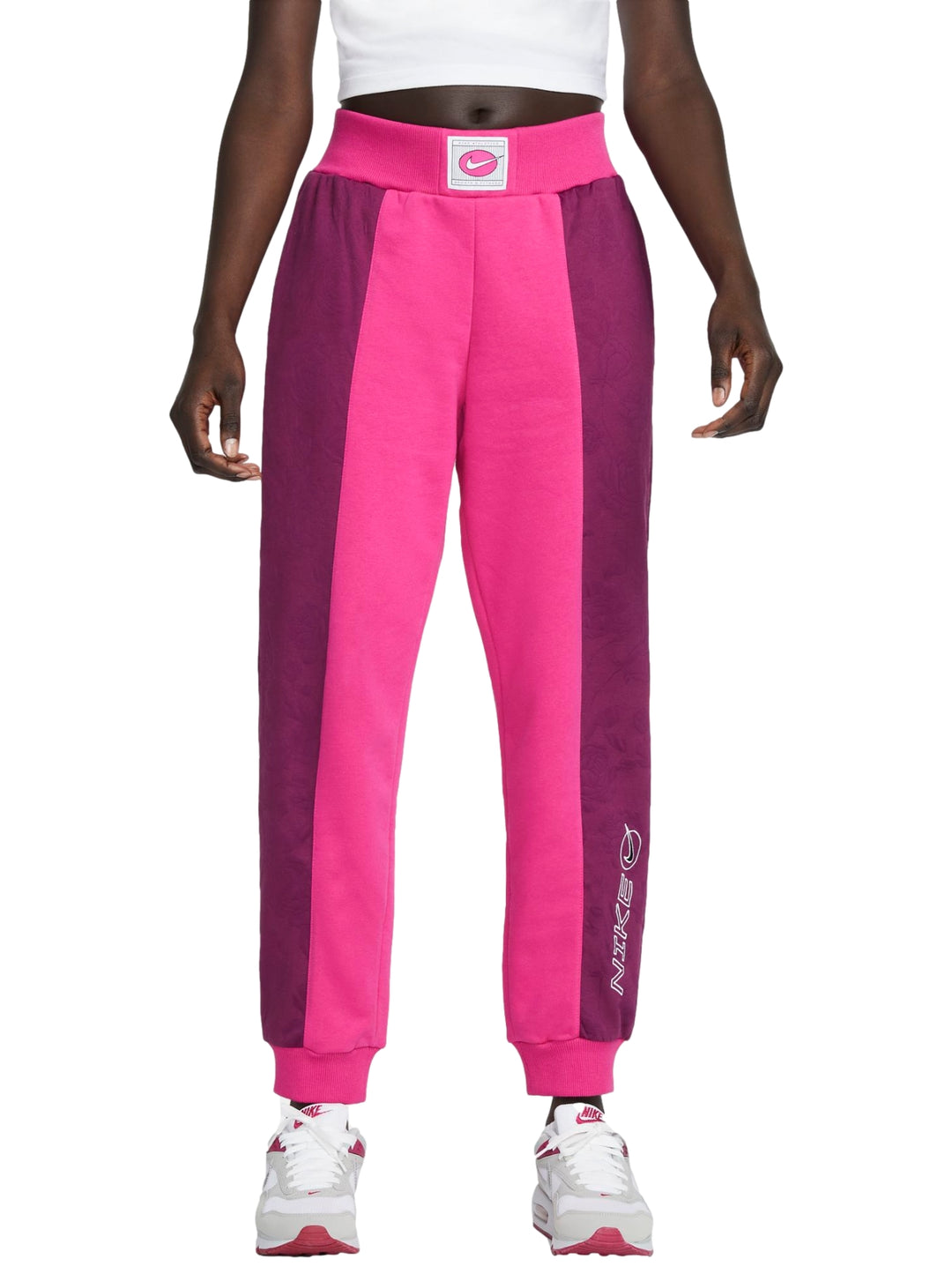 Pantalones deportivos Nike en colores rosa y morado con diseño de bloques laterales y cintura elástica.