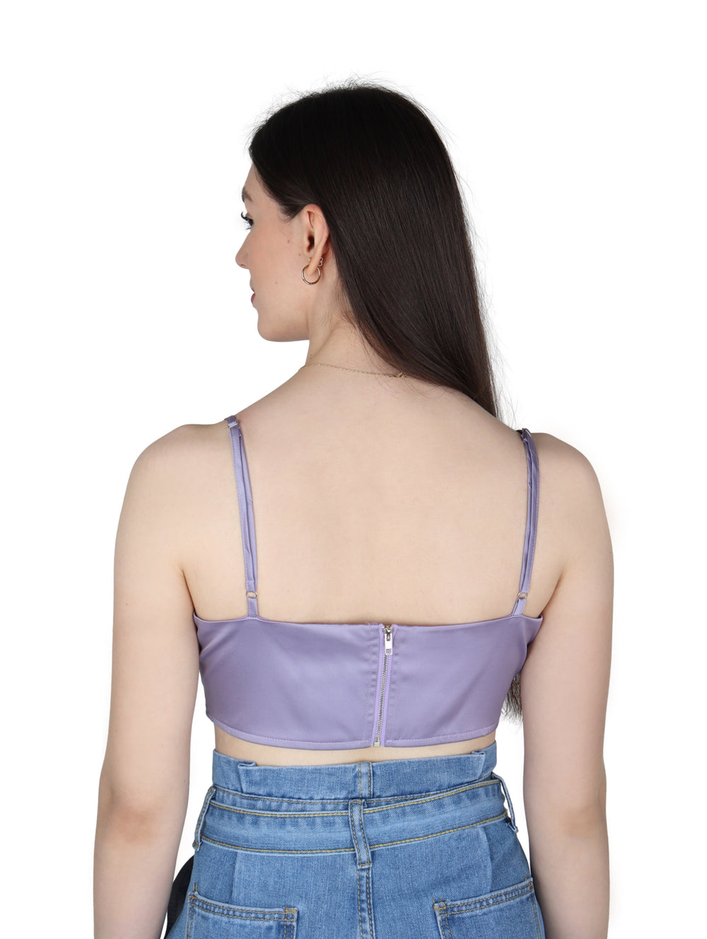 Mujer vistiendo un crop top color lavanda de tirantes con acabado satinado y pantalones vaqueros azules.
