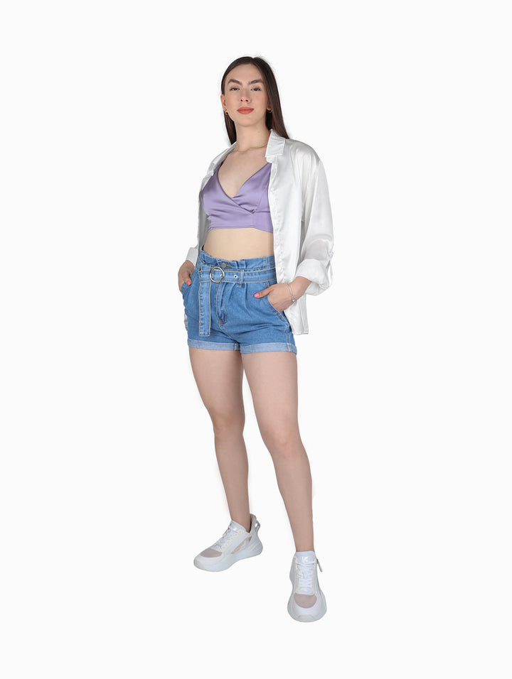 Mujer vistiendo un crop top color lavanda de tirantes con acabado satinado y pantalones vaqueros azules.
