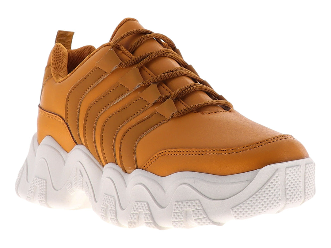 Tenis deportivos color mostaza con suela blanca gruesa y diseño ondulado.