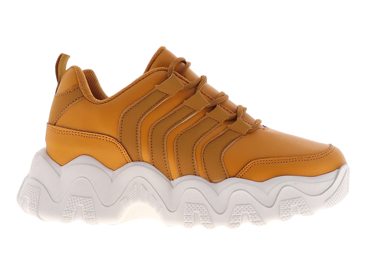 Tenis deportivos color mostaza con suela blanca gruesa y diseño ondulado.