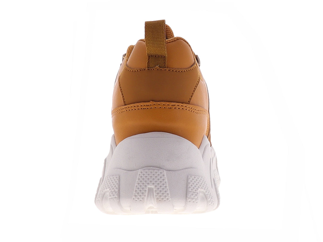Tenis deportivos color mostaza con suela blanca gruesa y diseño ondulado.