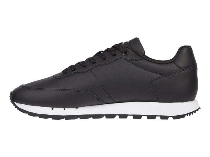 Tenis Tommy Hilfiger de cuero negro con banda tricolor en el costado y suela blanca.