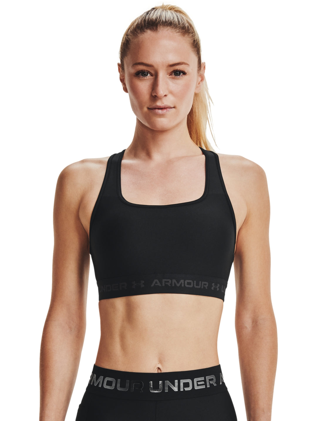 Mujer vistiendo un top deportivo Under Armour color negro con banda elástica gris en la base.
