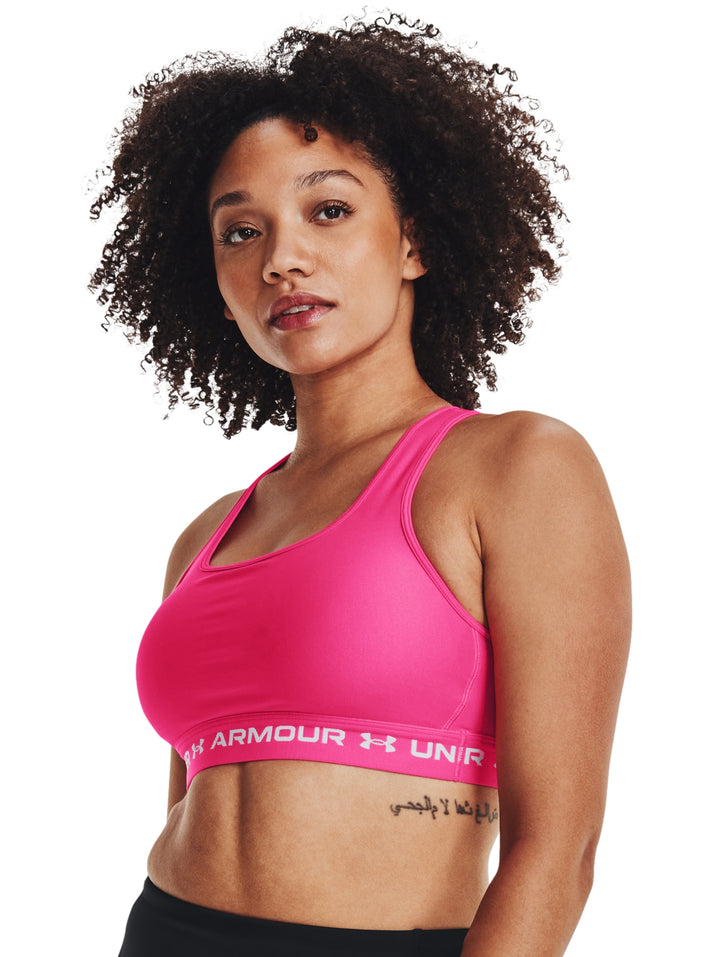 Mujer vistiendo un bra deportivo Under Armour color rosa con banda elástica blanca en la base.