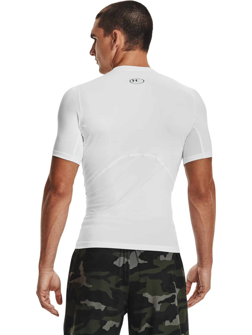 Hombre vistiendo camiseta deportiva de compresión Under Armour color blanco con logo negro en el pecho.