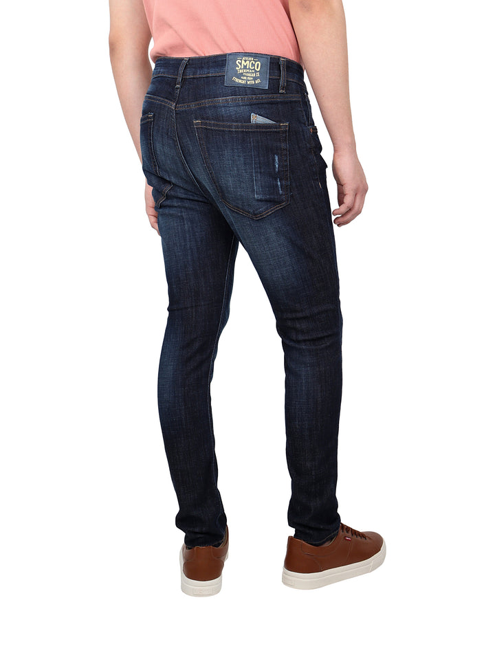 Pantalones jeans azul oscuro con detalles de destrucción y corte ajustado.