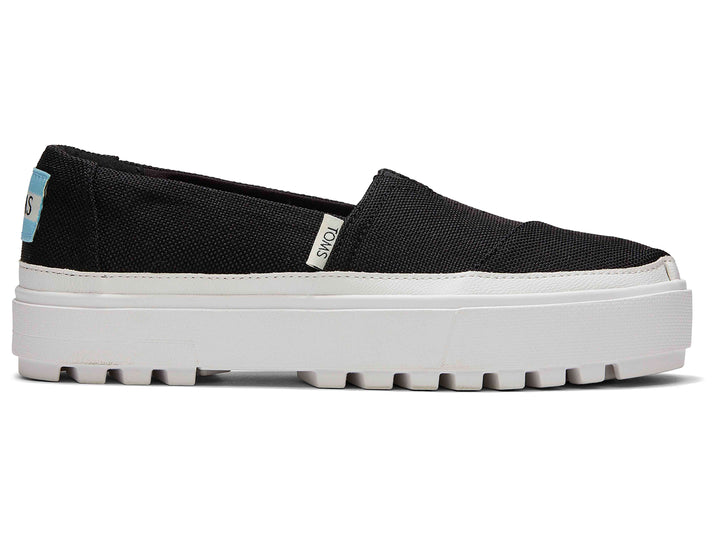 Zapatos slip-on TOMS color negro con suela blanca de plataforma gruesa.
