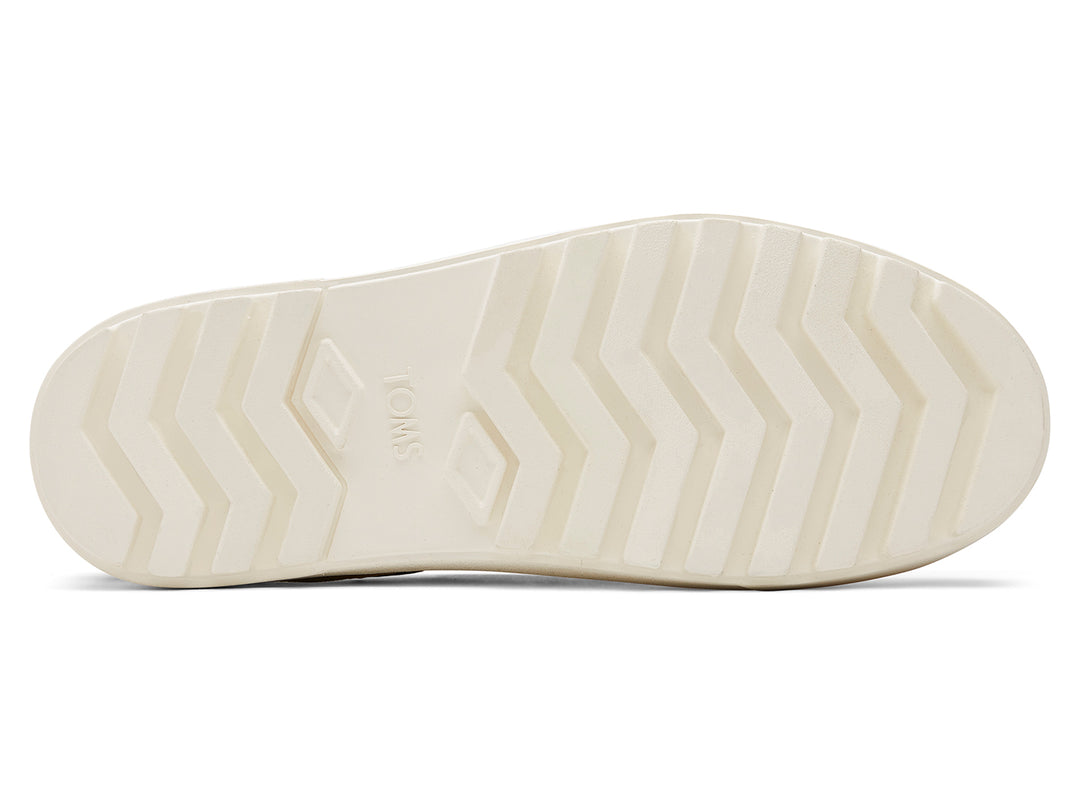 Zapatos slip-on TOMS color negro con suela blanca de plataforma gruesa.