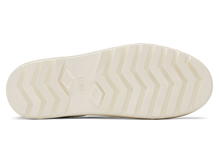 Zapatos slip-on TOMS color negro con suela blanca de plataforma gruesa.