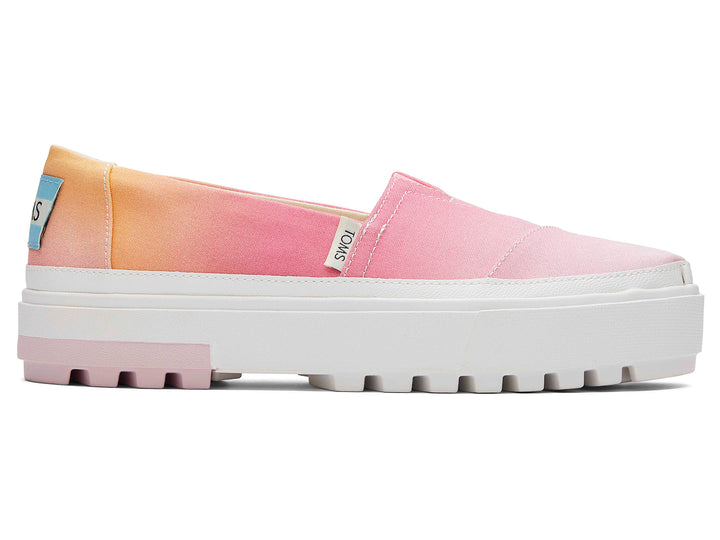 Zapato TOMS estilo slip-on con plataforma blanca y diseño en degradado de colores naranja a rosa.