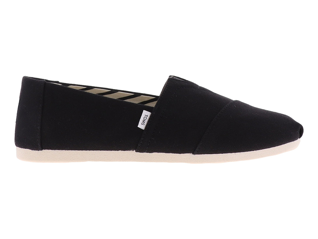 Zapato plano slip-on TOMS de tela negra con suela blanca.