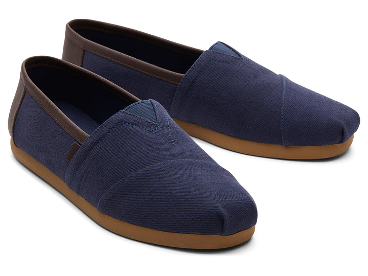 Par de zapatos planos estilo slip-on en color azul marino con suela color café.
