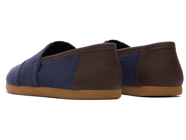 Par de zapatos planos estilo slip-on en color azul marino con suela color café.