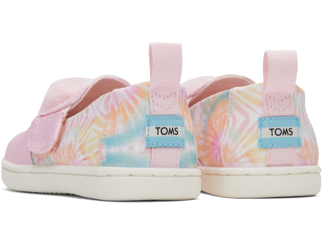 Zapatos infantiles TOMS color rosa con diseño de unicornio, pompones y detalles en tie-dye.