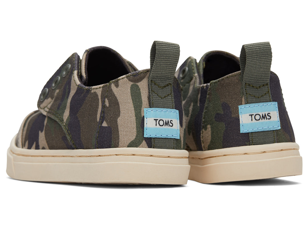 Par de zapatos infantiles TOMS con estampado de camuflaje en tonos verdes y beige, suela clara y diseño casual.
