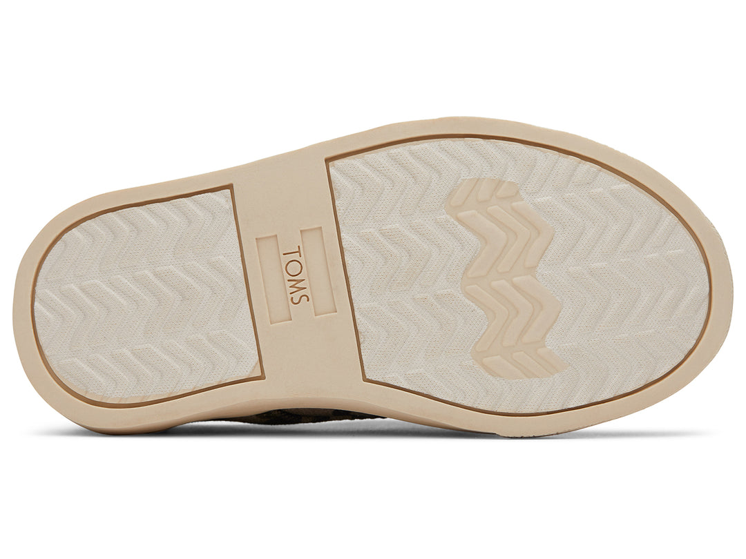 Par de zapatos infantiles TOMS con estampado de camuflaje en tonos verdes y beige, suela clara y diseño casual.