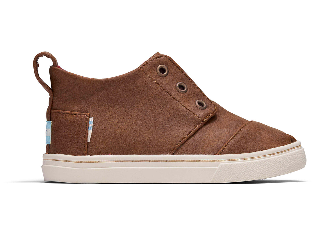 Zapato casual infantil TOMS color café toffee con suela blanca y diseño sin cordones.