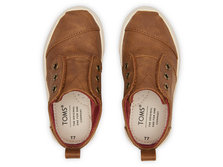 Zapato casual infantil TOMS color café toffee con suela blanca y diseño sin cordones.