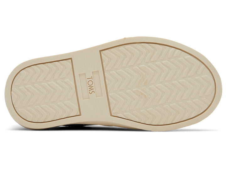 Zapato casual infantil TOMS color café toffee con suela blanca y diseño sin cordones.