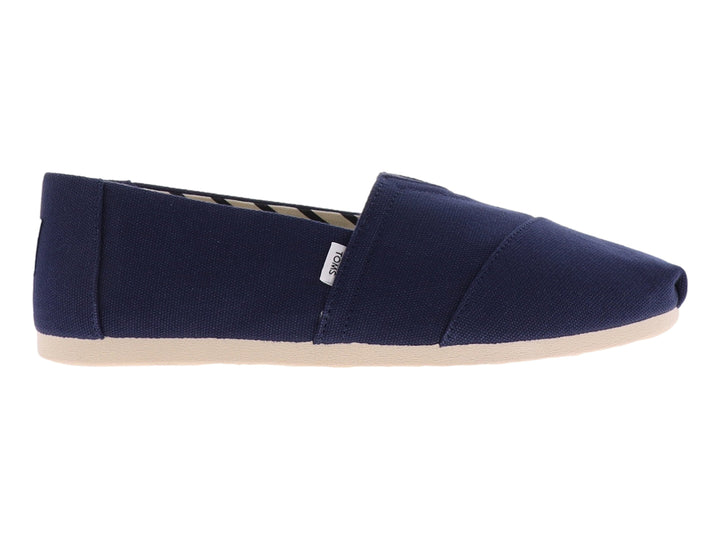 Zapato plano slip-on TOMS en color azul marino con suela beige y forro interior a rayas.