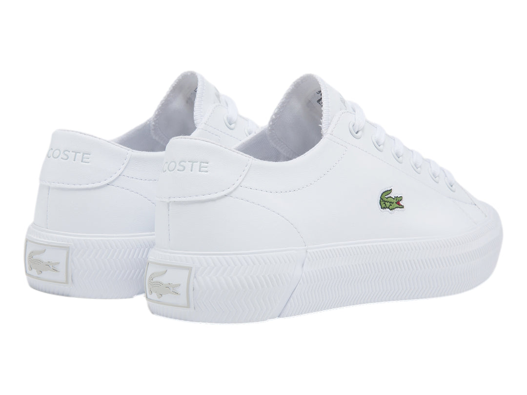 Tenis blancos Lacoste con logotipo de cocodrilo verde y suela blanca.