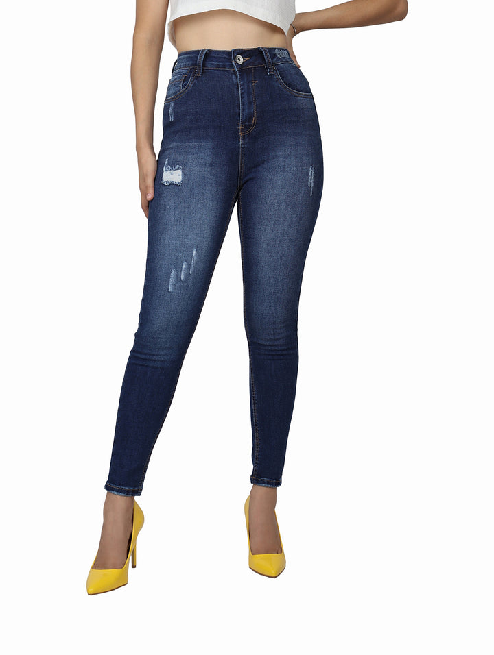 Mujer vistiendo pantalón de mezclilla azul oscuro ajustado con detalles desgastados.