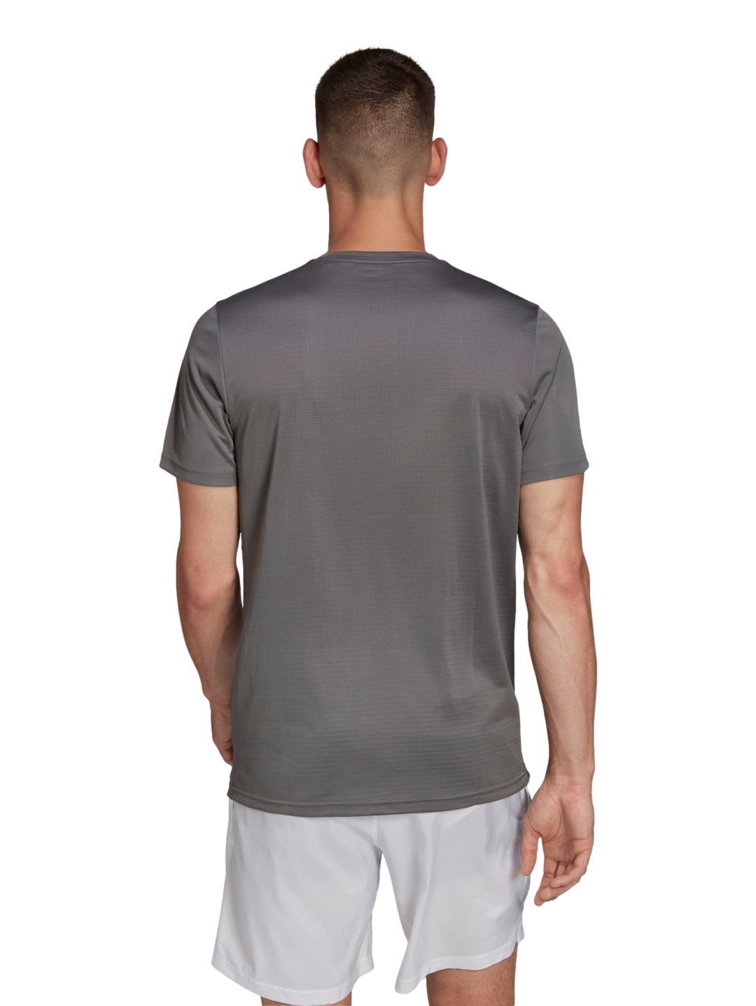 Hombre vistiendo playera deportiva Adidas color gris con detalles reflectantes y shorts blancos.