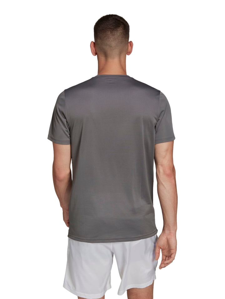 Hombre vistiendo playera deportiva Adidas color gris con detalles reflectantes y shorts blancos.