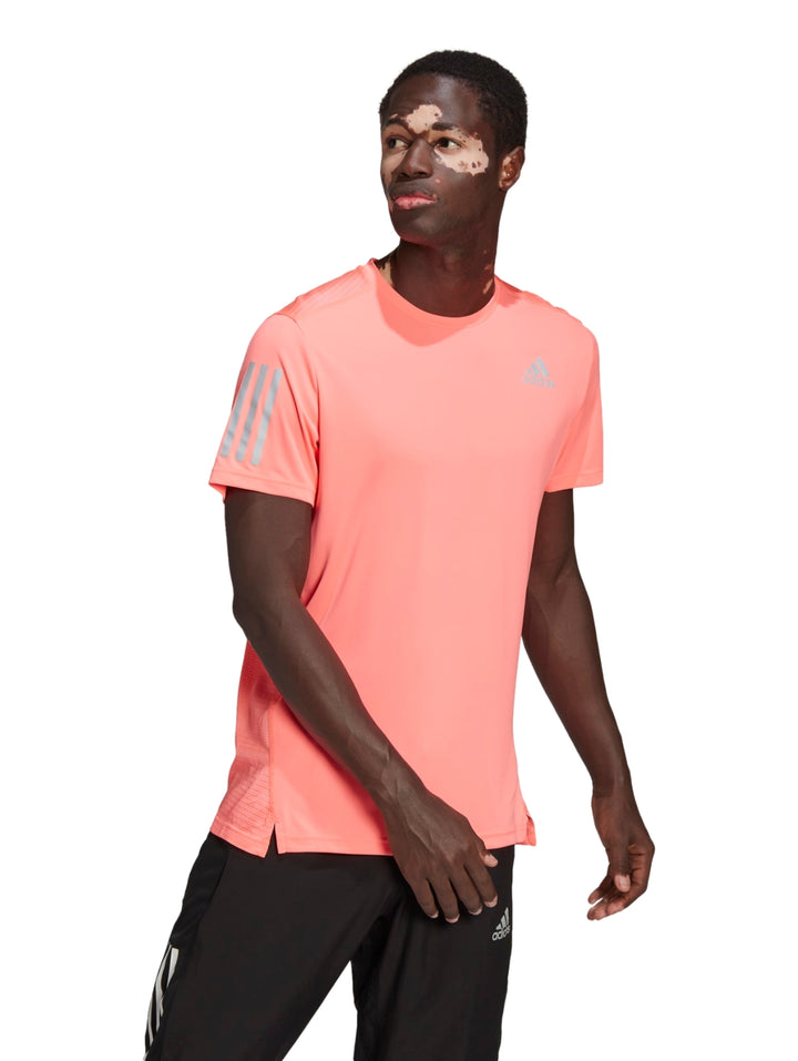 Hombre vistiendo playera deportiva Adidas color rojo ácido con detalles reflectantes en plata.