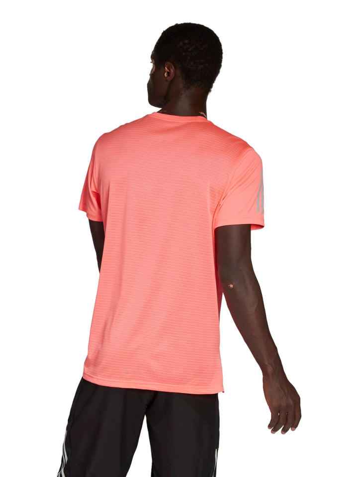 Hombre vistiendo playera deportiva Adidas color rojo ácido con detalles reflectantes en plata.