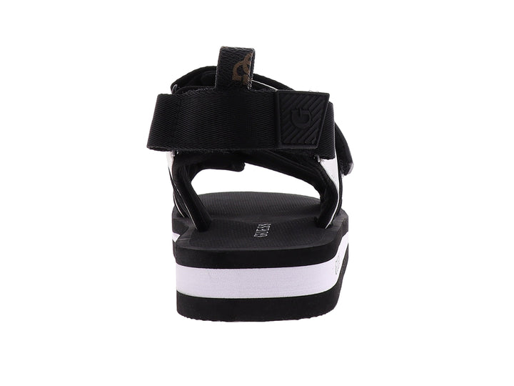 Sandalia gladiador Guess color negro y blanco con correas ajustables y suela plana.