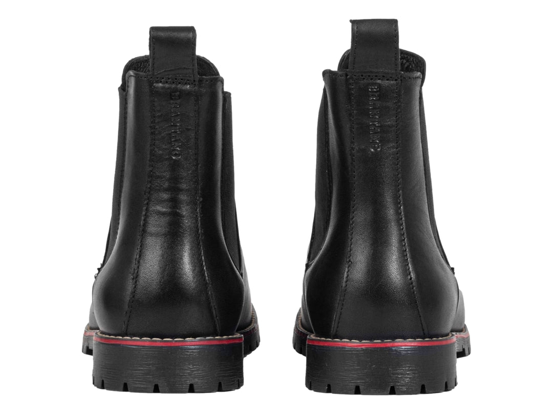 Botín negro de piel para hombre con detalle rojo en la suela y panel elástico lateral.