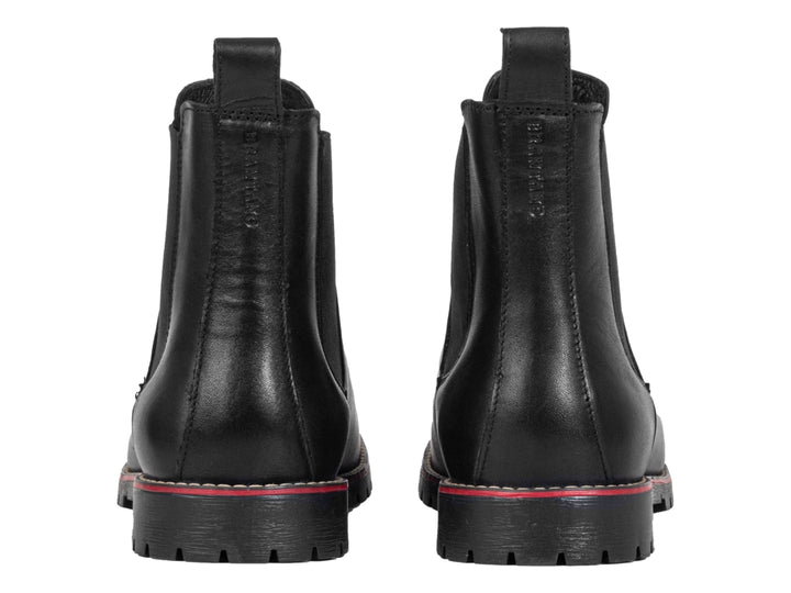 Botín negro de piel para hombre con detalle rojo en la suela y panel elástico lateral.