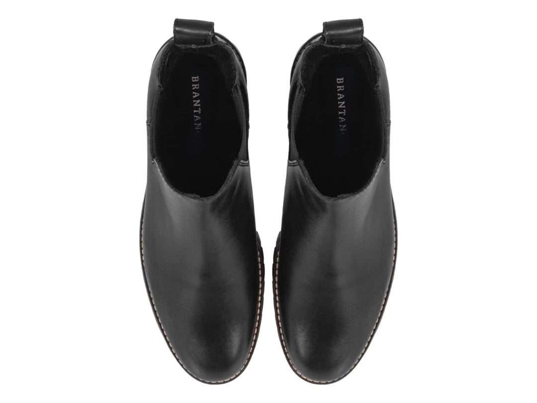 Botín negro de piel para hombre con detalle rojo en la suela y panel elástico lateral.