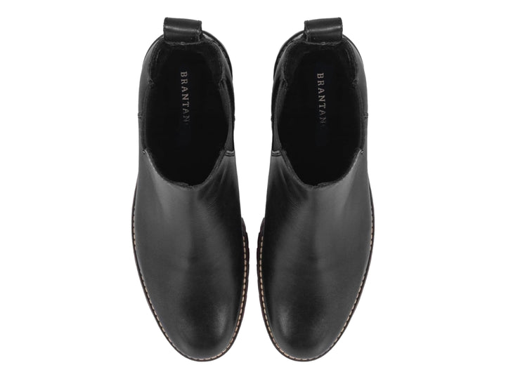 Botín negro de piel para hombre con detalle rojo en la suela y panel elástico lateral.