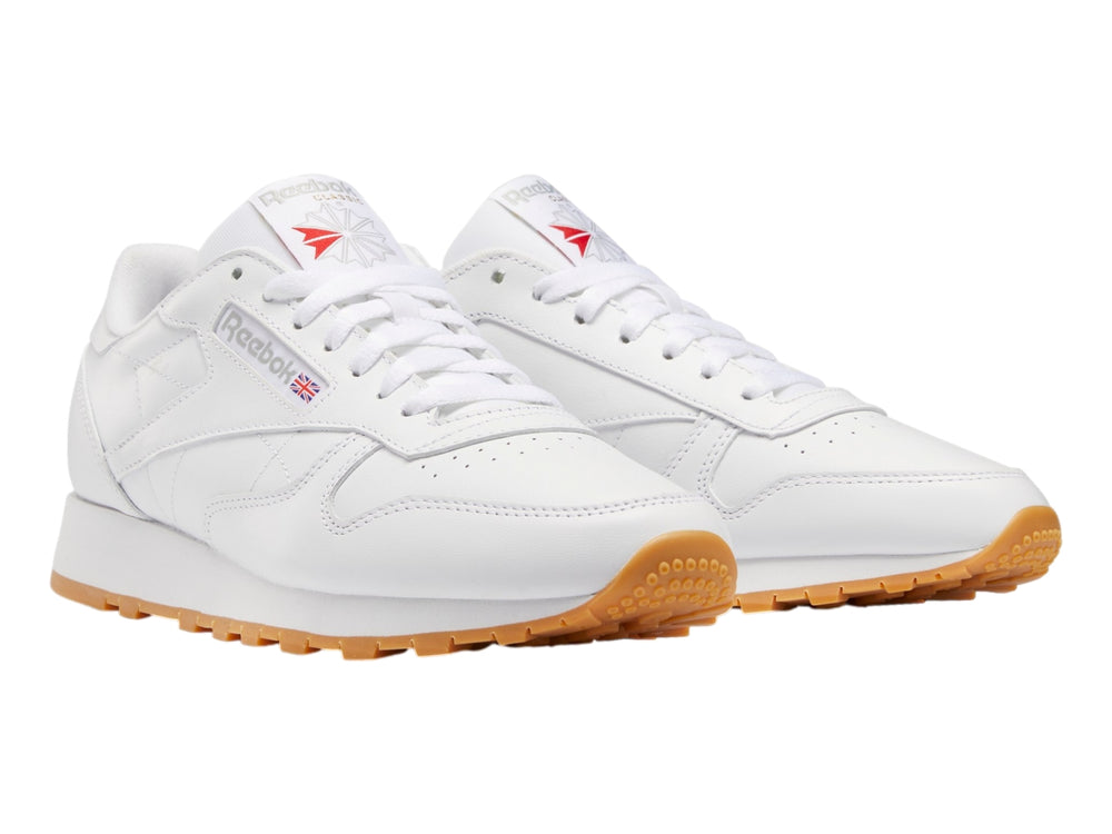 Tenis Reebok Classic Leather color blanco con suela de goma color miel.