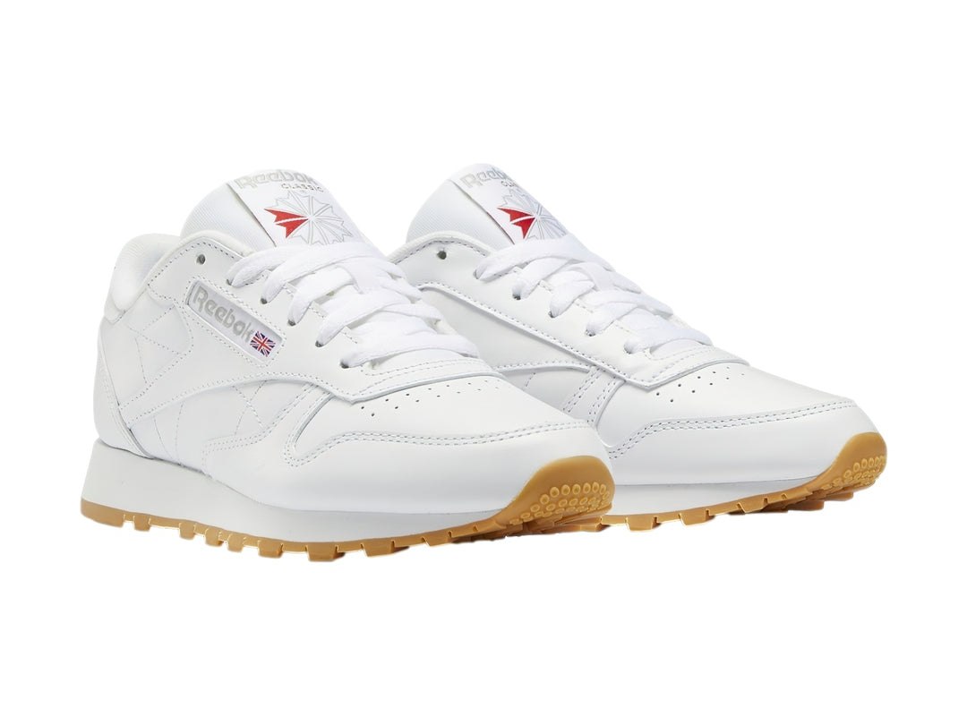 Tenis Reebok Classic Leather blancos con suela de goma color marrón.