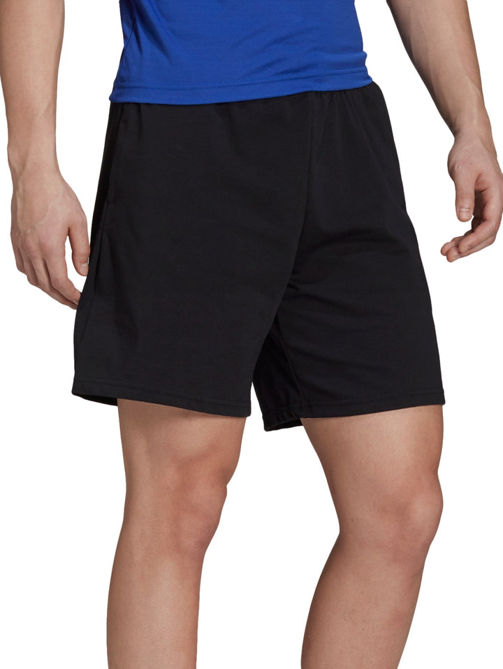 Hombre vistiendo shorts deportivos color negro de la marca Adidas.