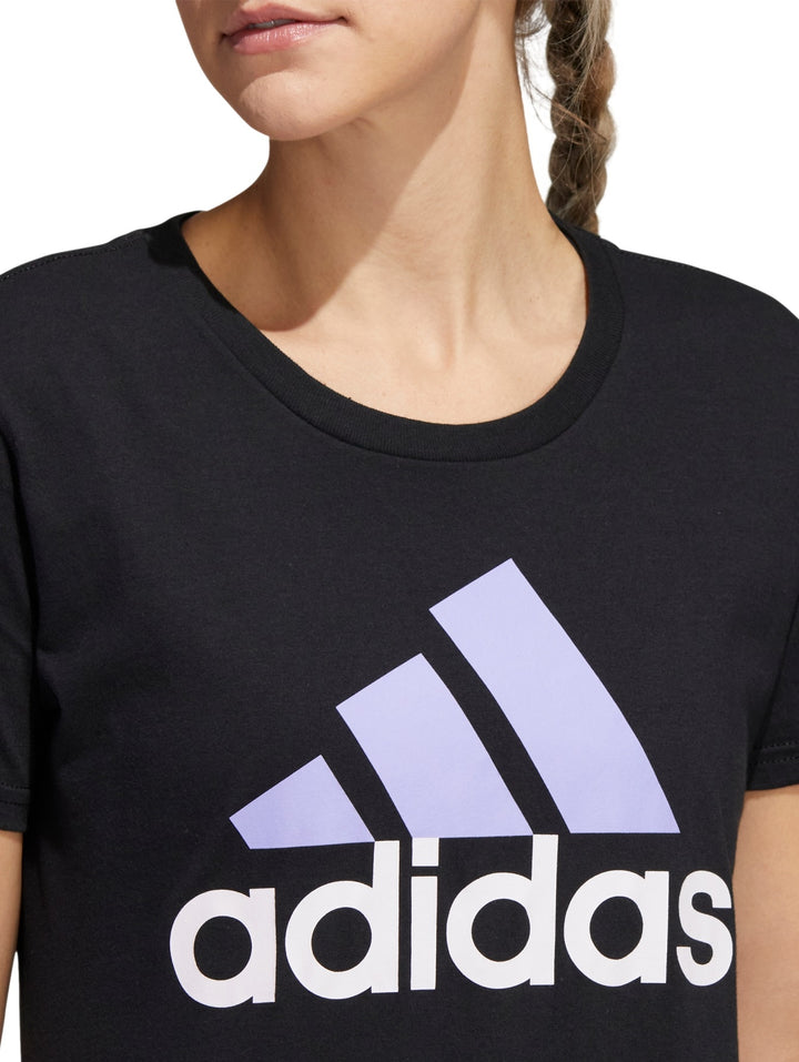 Mujer vistiendo playera deportiva Adidas color negro con logotipo lila en el pecho.