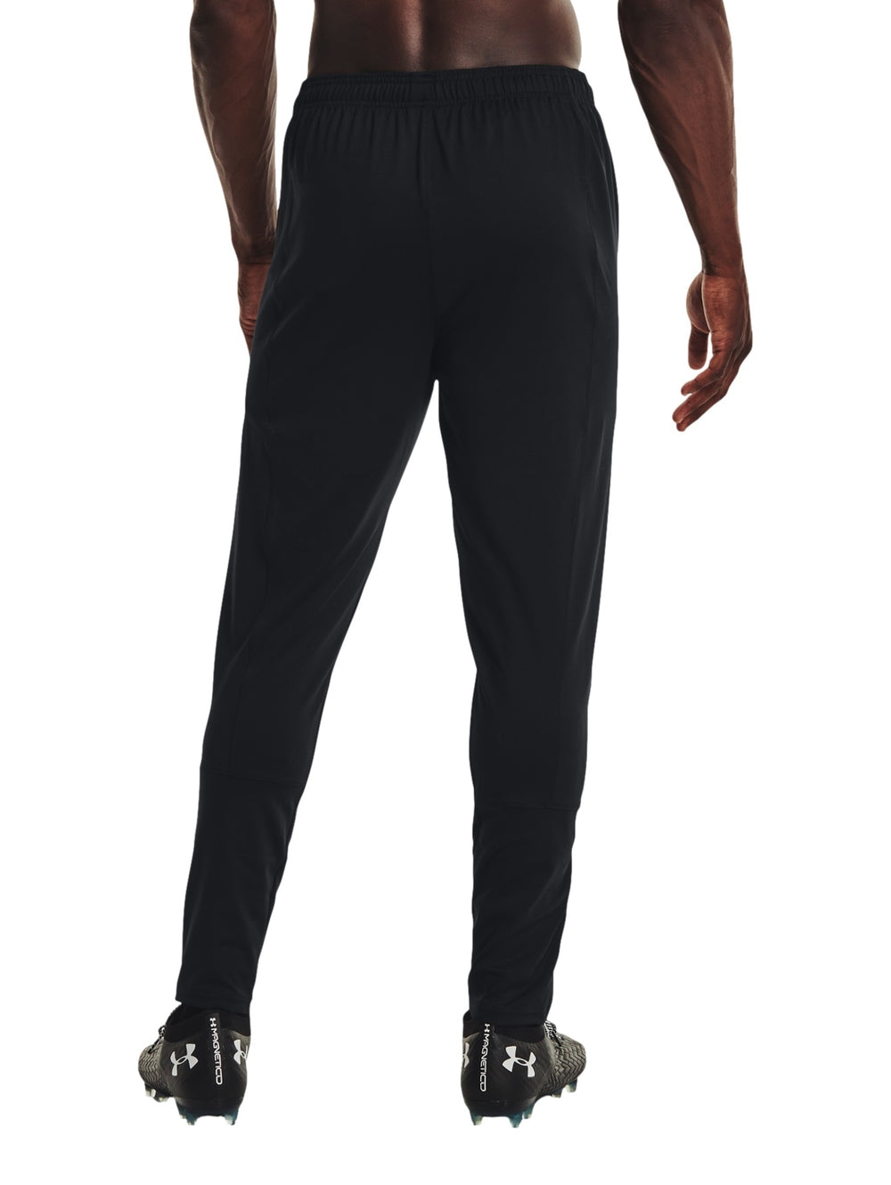 Hombre vistiendo pantalones deportivos Under Armour color negro con logo blanco en la pierna izquierda.