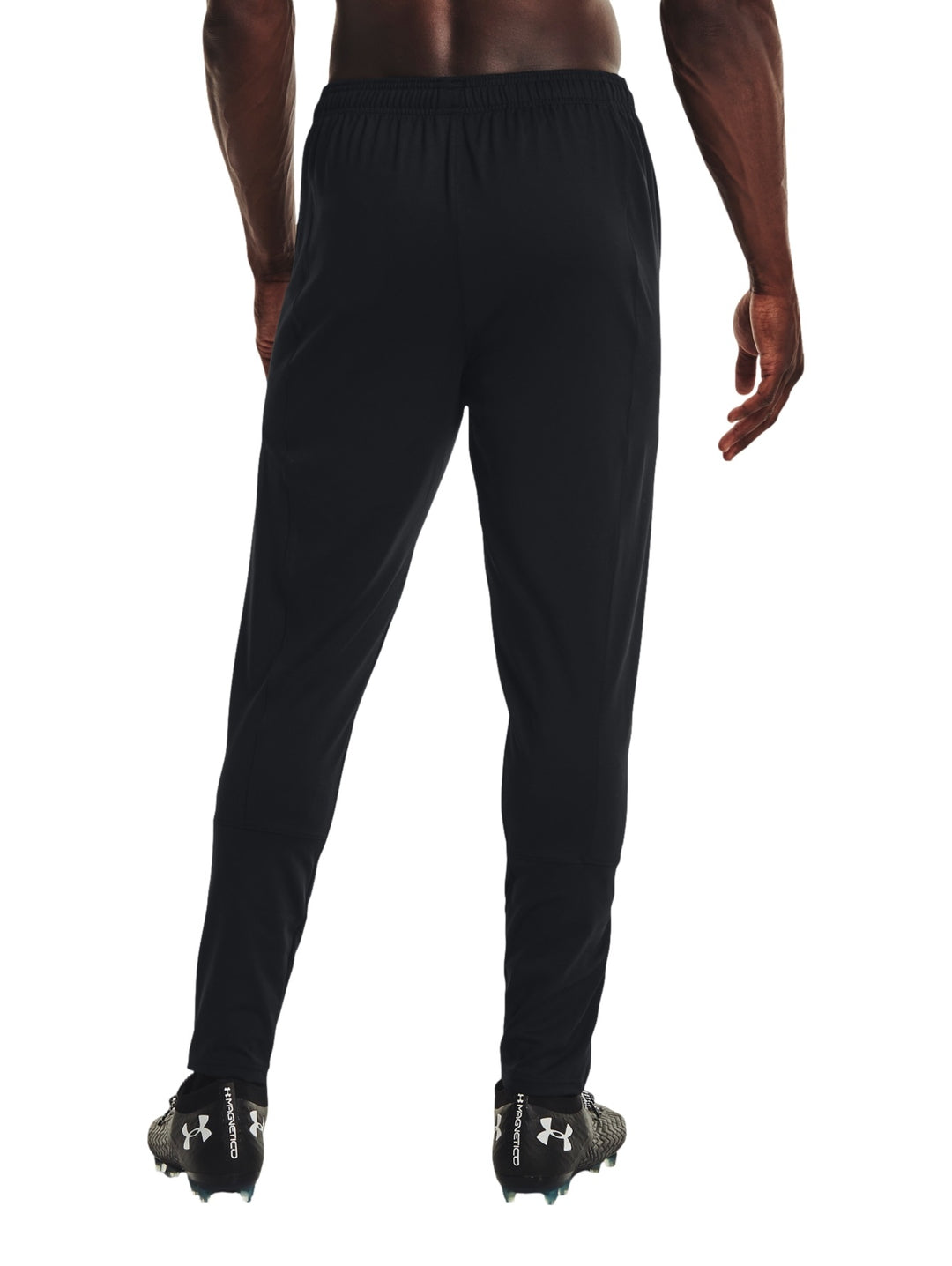Hombre vistiendo pantalones deportivos Under Armour color negro con logo blanco en la pierna izquierda.