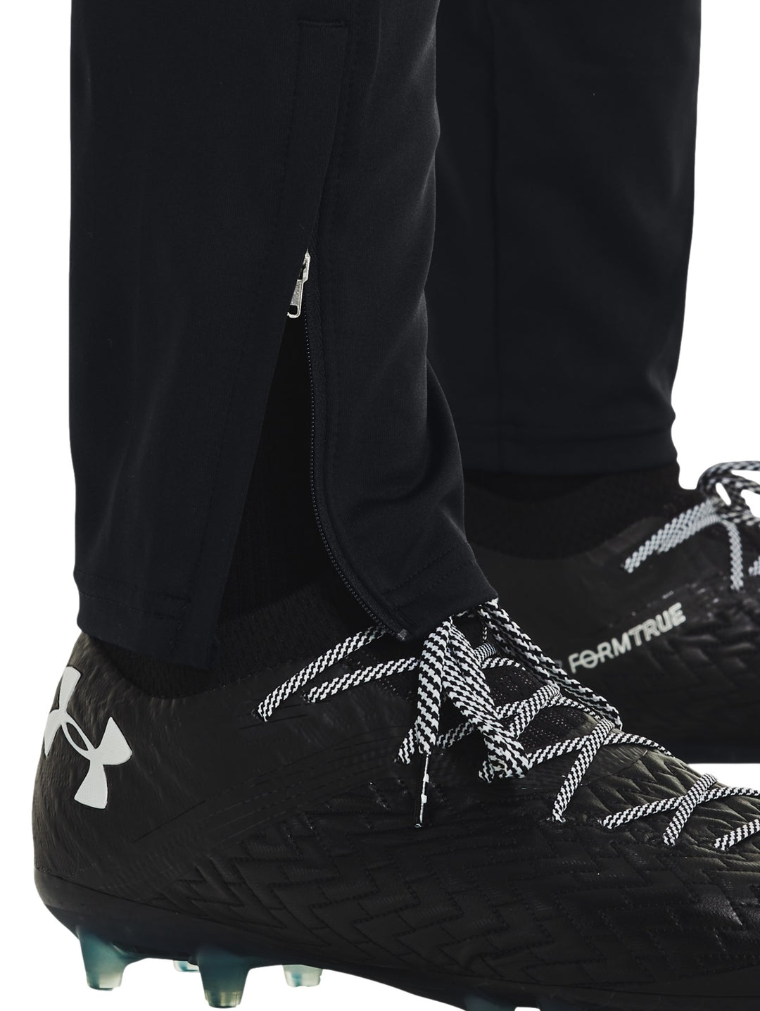 Hombre vistiendo pantalones deportivos Under Armour color negro con logo blanco en la pierna izquierda.