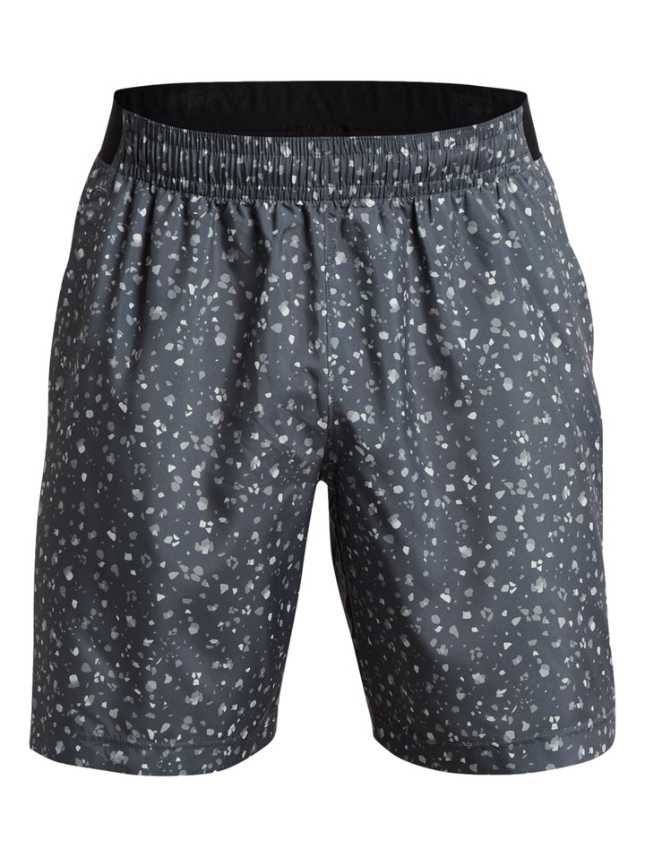 Hombre vistiendo shorts deportivos Under Armour color gris oscuro con estampado de puntos blancos.