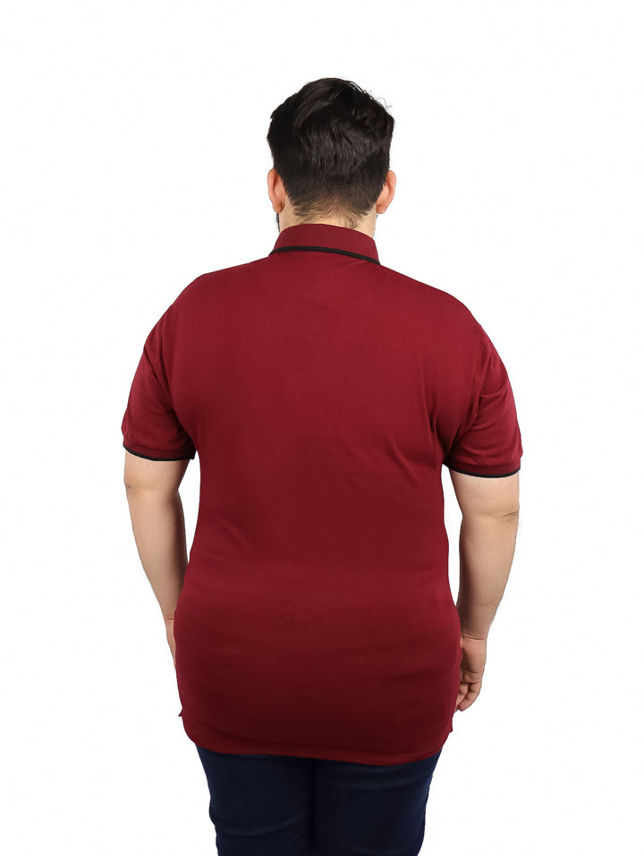 Hombre vistiendo una playera polo color vino con detalles negros en el cuello y mangas.
