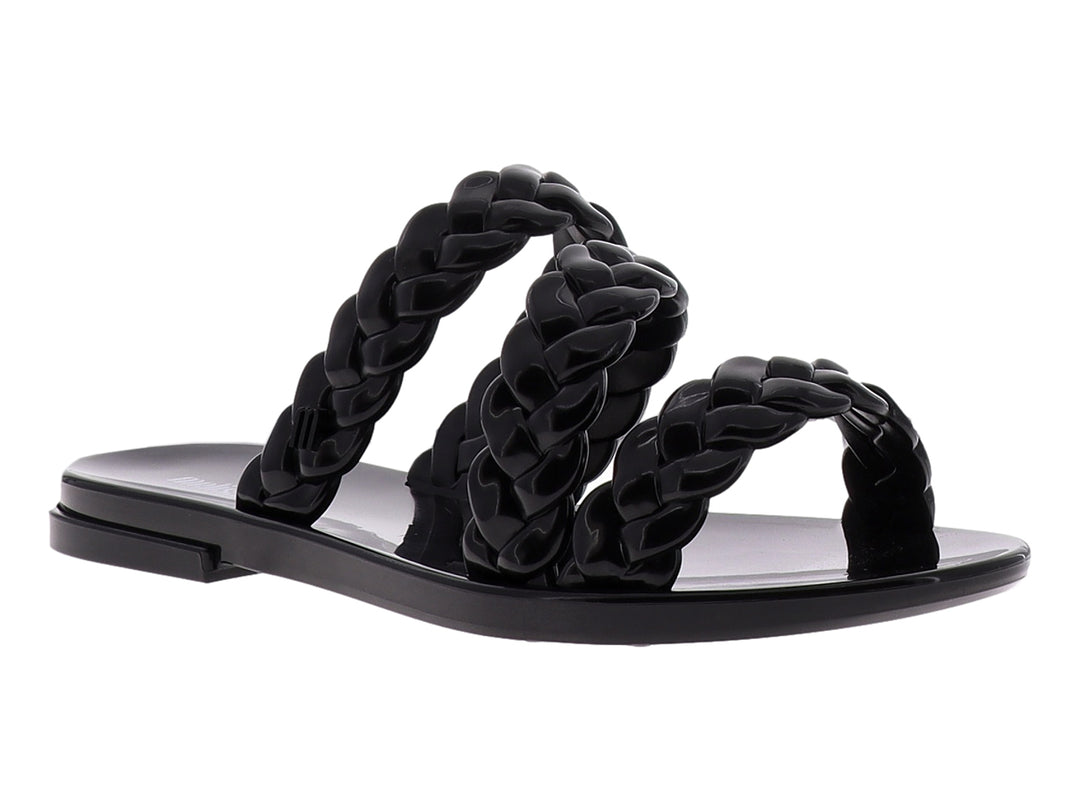 Sandalia Melissa color negro con tiras trenzadas y suela plana brillante.