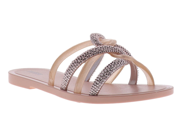 Sandalia Melissa color rosa con tiras entrelazadas decoradas con brillantes y suela plana.