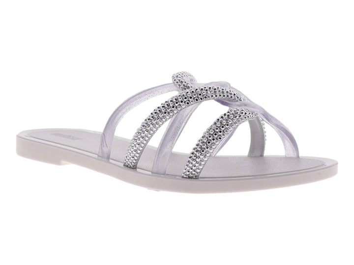 Sandalia Melissa blanca brillante con tiras cruzadas decoradas con cristales y suela plana.