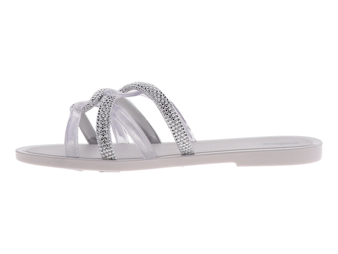 Sandalia Melissa blanca brillante con tiras cruzadas decoradas con cristales y suela plana.